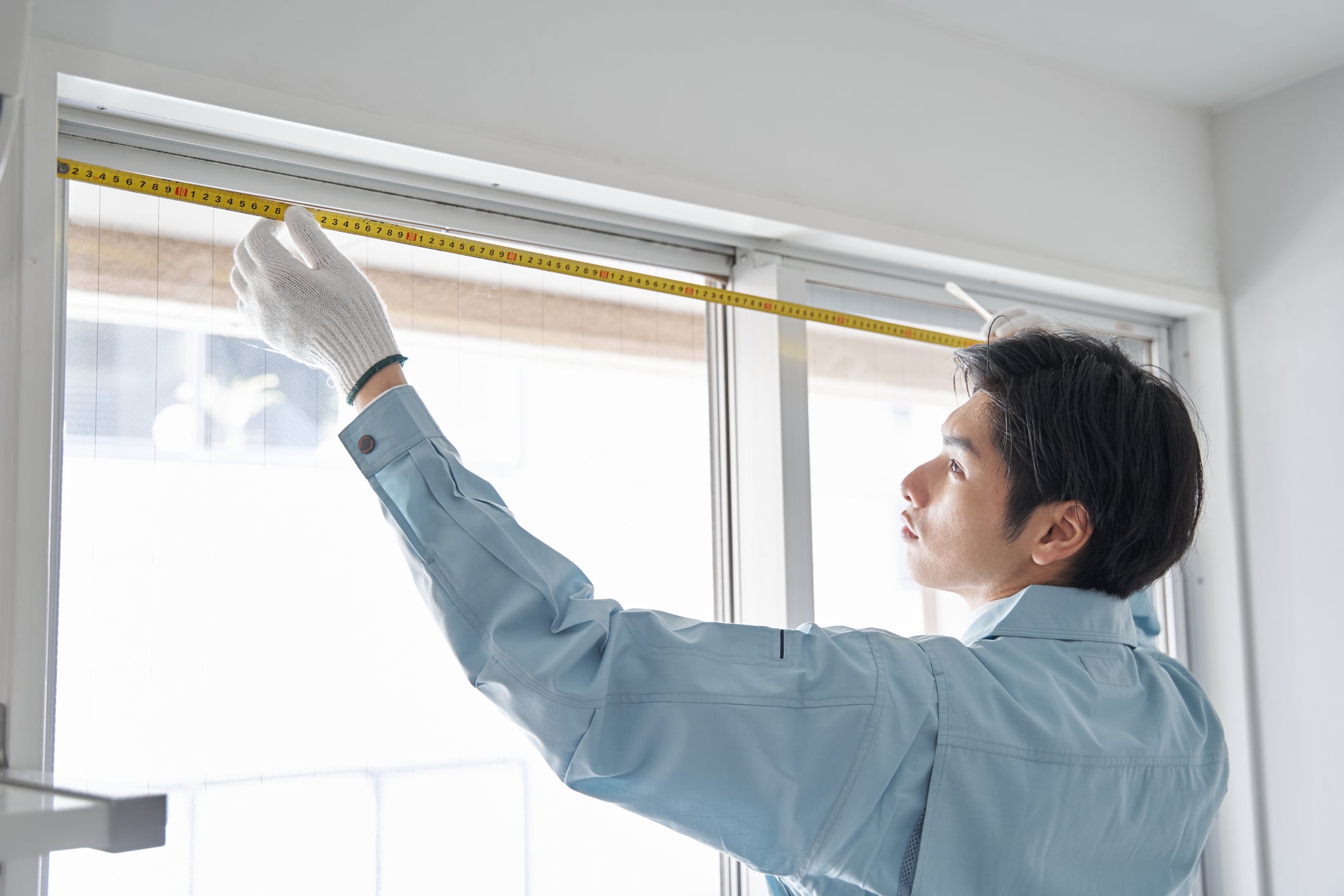 The Permasol's male worker taking measurements of a room's windows